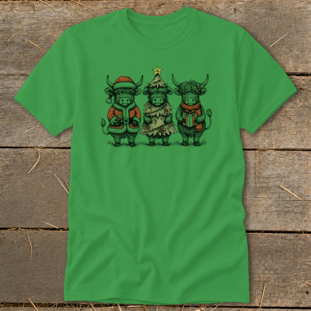 Three highland cows in Christmas attire stand together on a green t-shirt.