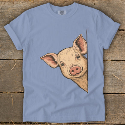 Light blue t-shirt with a drawing of a smiling pig peeking from the side.