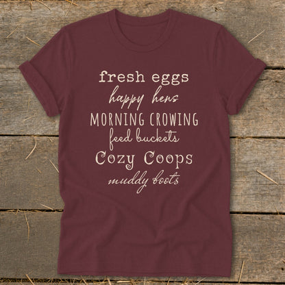 Maroon t-shirt with white text: fresh eggs, happy hens, MORNING CROWING, feed buckets, Cozy Coops, muddy boots.