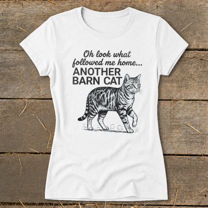 White t-shirt with black text and barn cat illustration reading "Oh look what followed me home... ANOTHER BARN CAT".