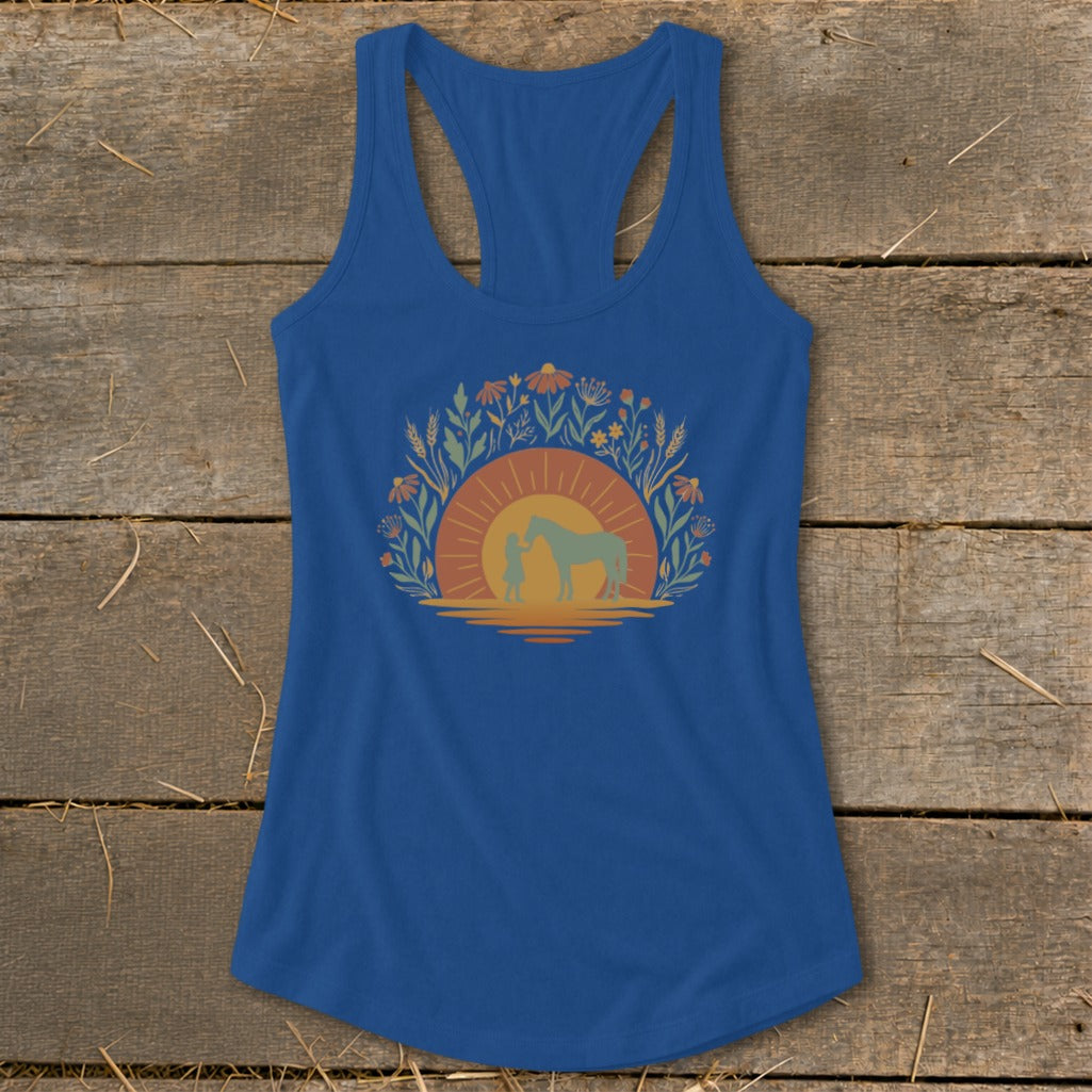 Blue tank top with a graphic of a person and horse at sunset surrounded by flowers.