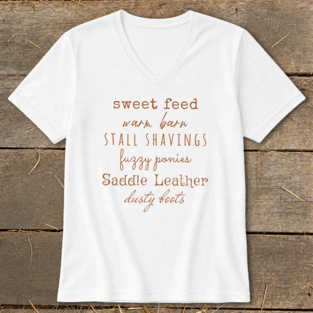 White t-shirt with brown text: sweet feed, warm barn, stall shavings, fuzzy ponies, saddle leather, dusty boots.