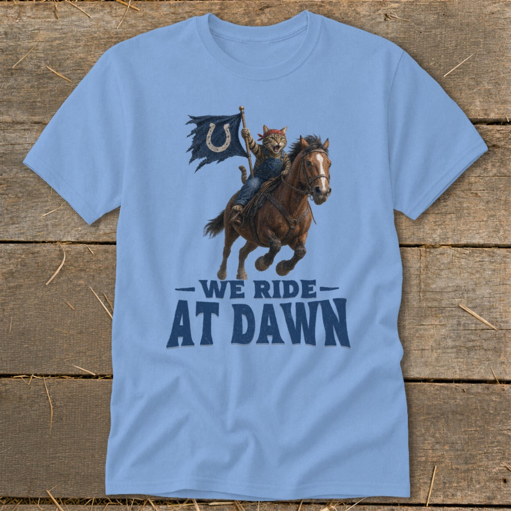 Light blue t-shirt with a cat on a horse holding a flag, text reads "WE RIDE AT DAWN".