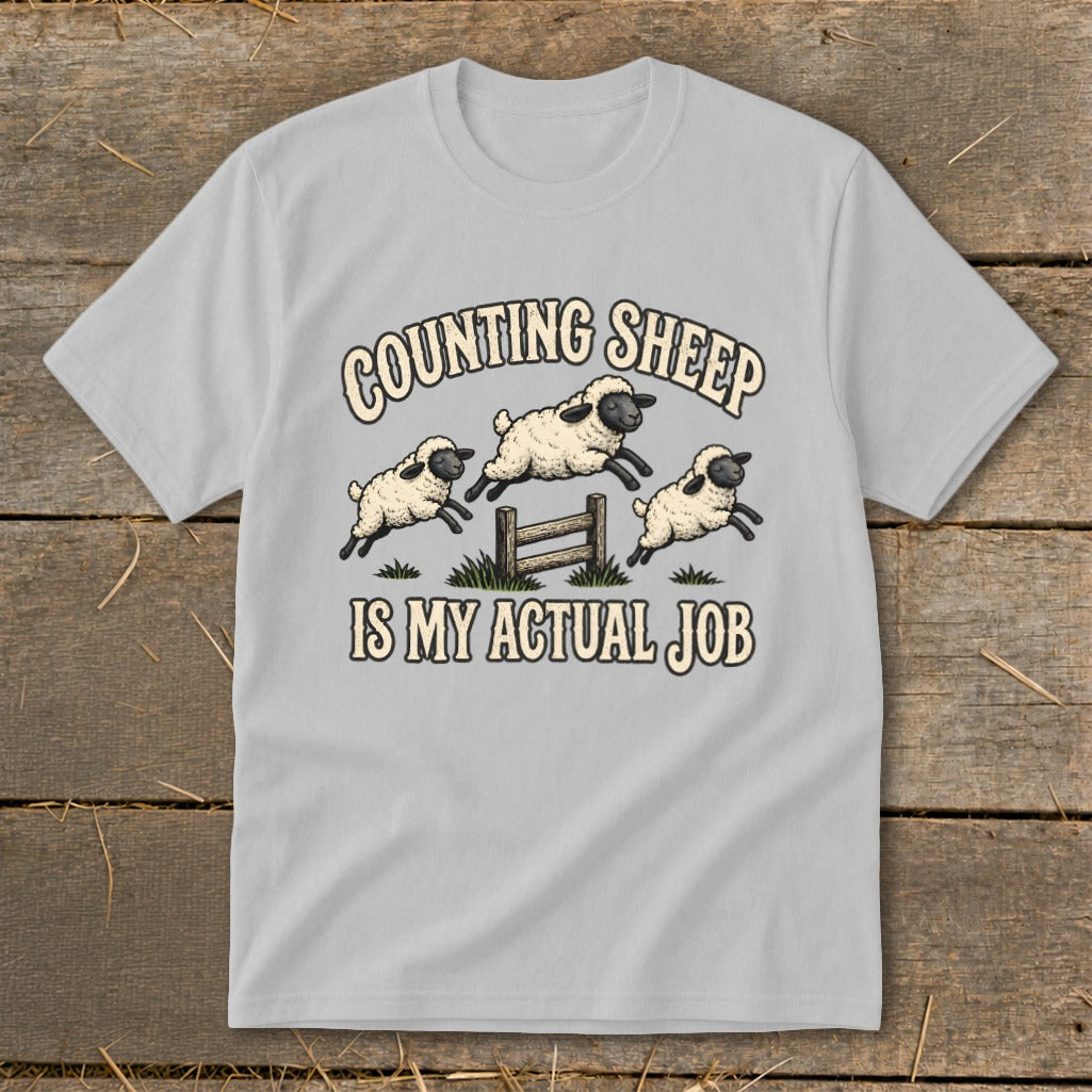 Light grey t-shirt with "COUNTING SHEEP IS MY ACTUAL JOB" and jumping sheep graphic.