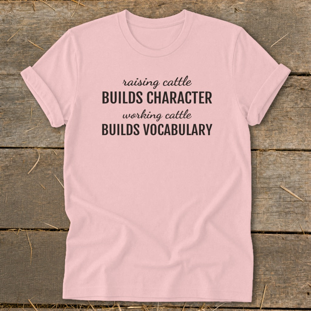 Pink t-shirt with text "raising cattle BUILDS CHARACTER working cattle BUILDS VOCABULARY".