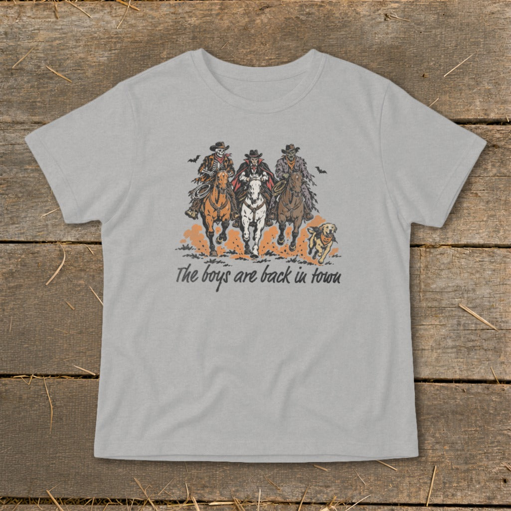 Three skeleton cowboys ride horses with a dog and the text "The boys are back in town."