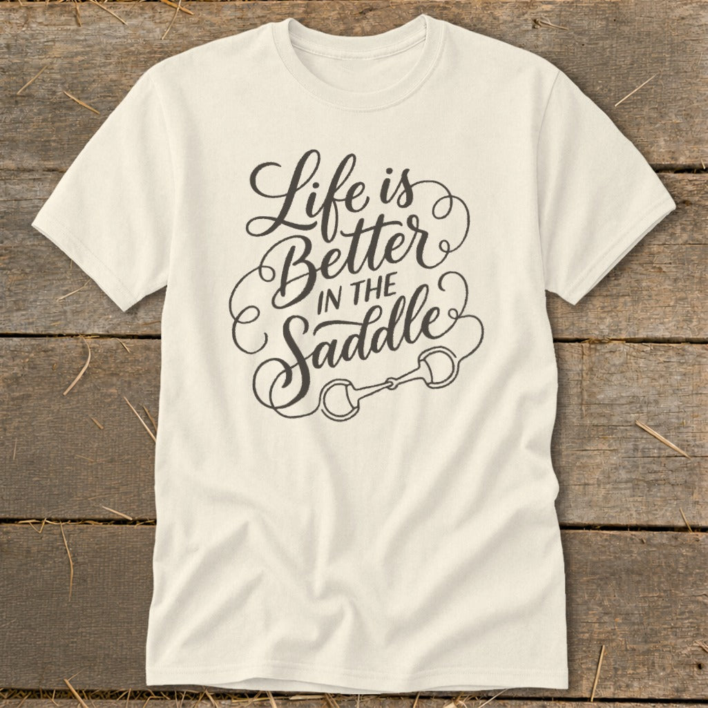 Cream t-shirt with "Life is Better in the Saddle" text and a horse bit graphic.