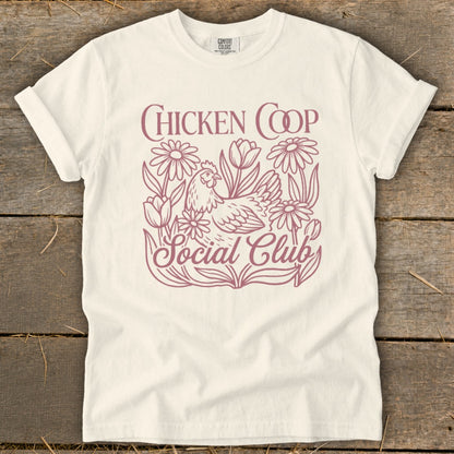 Cream t-shirt with "Chicken Coop Social Club" text and a chicken surrounded by flowers.