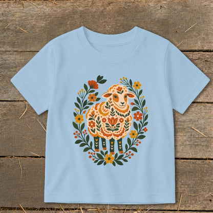 Light blue t-shirt with a folk art sheep illustration surrounded by flowers.
