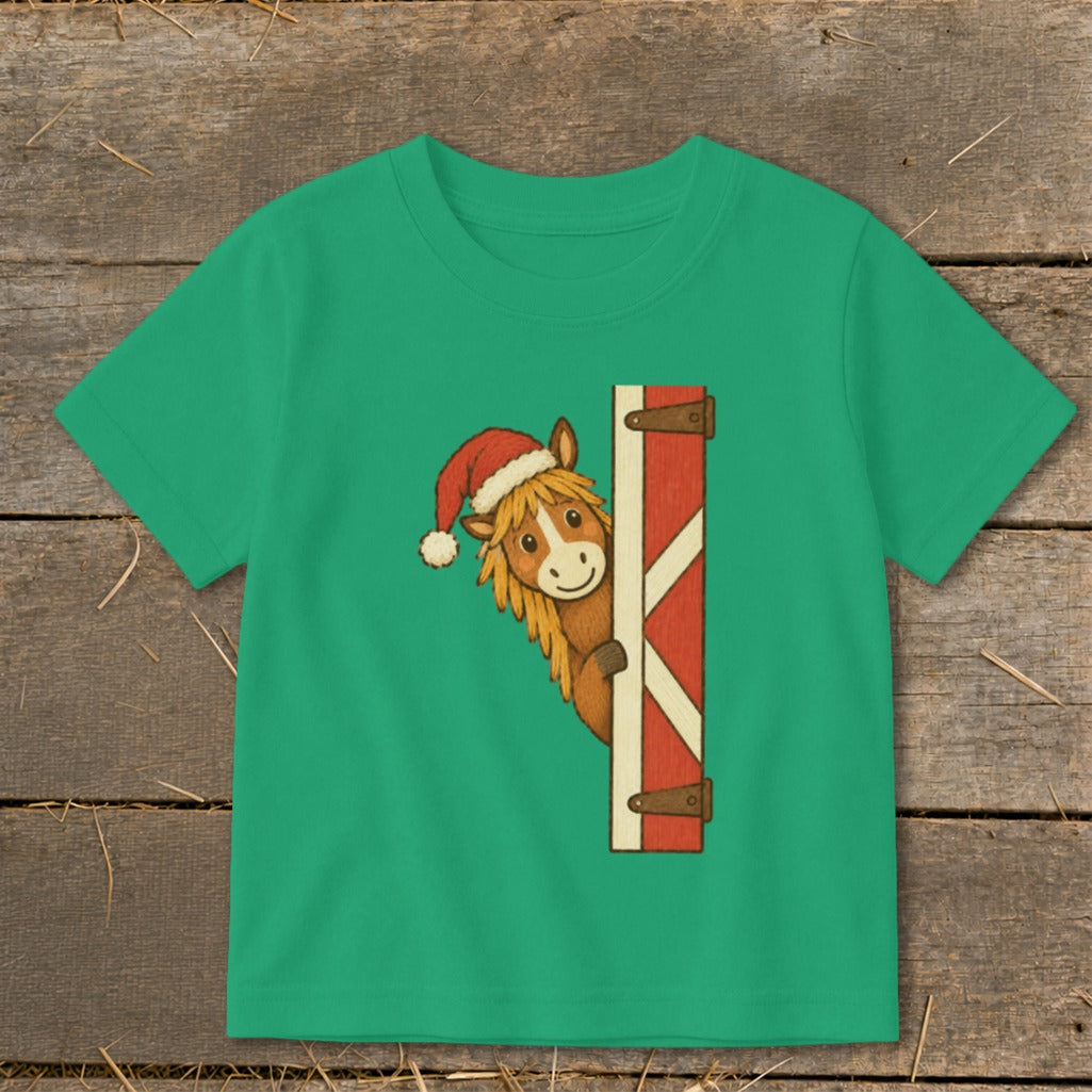 Green t-shirt with a cartoon horse wearing a Santa hat peeking behind a barn door.