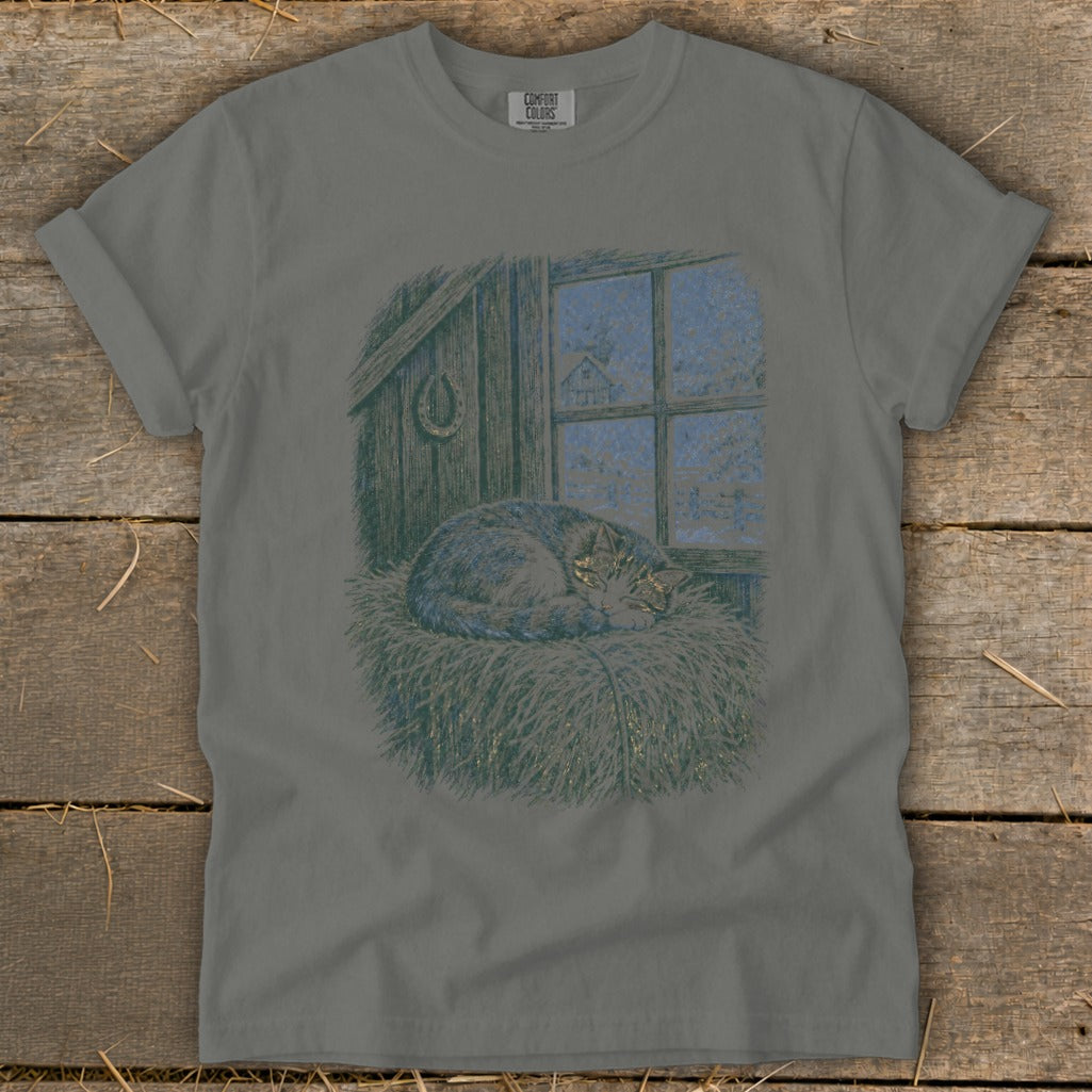 Gray t-shirt with illustration of a cat sleeping on hay by a snowy window.