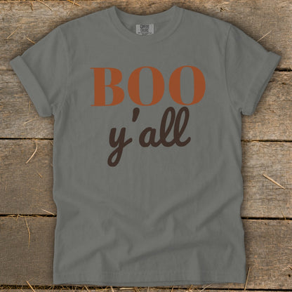Gray t-shirt with "Boo y'all" text in orange and brown on a wooden background.