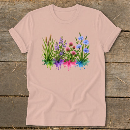 Light pink t-shirt featuring a watercolor graphic of wildflowers and grasses with colorful paint splatters.