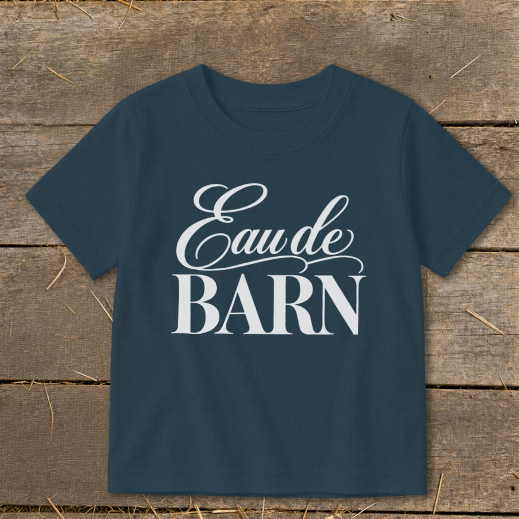 Navy t-shirt with white text "Eau de BARN" on a wooden background.