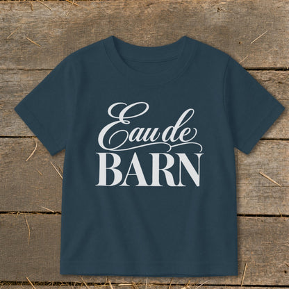 Navy t-shirt with white text "Eau de BARN" on a wooden background.