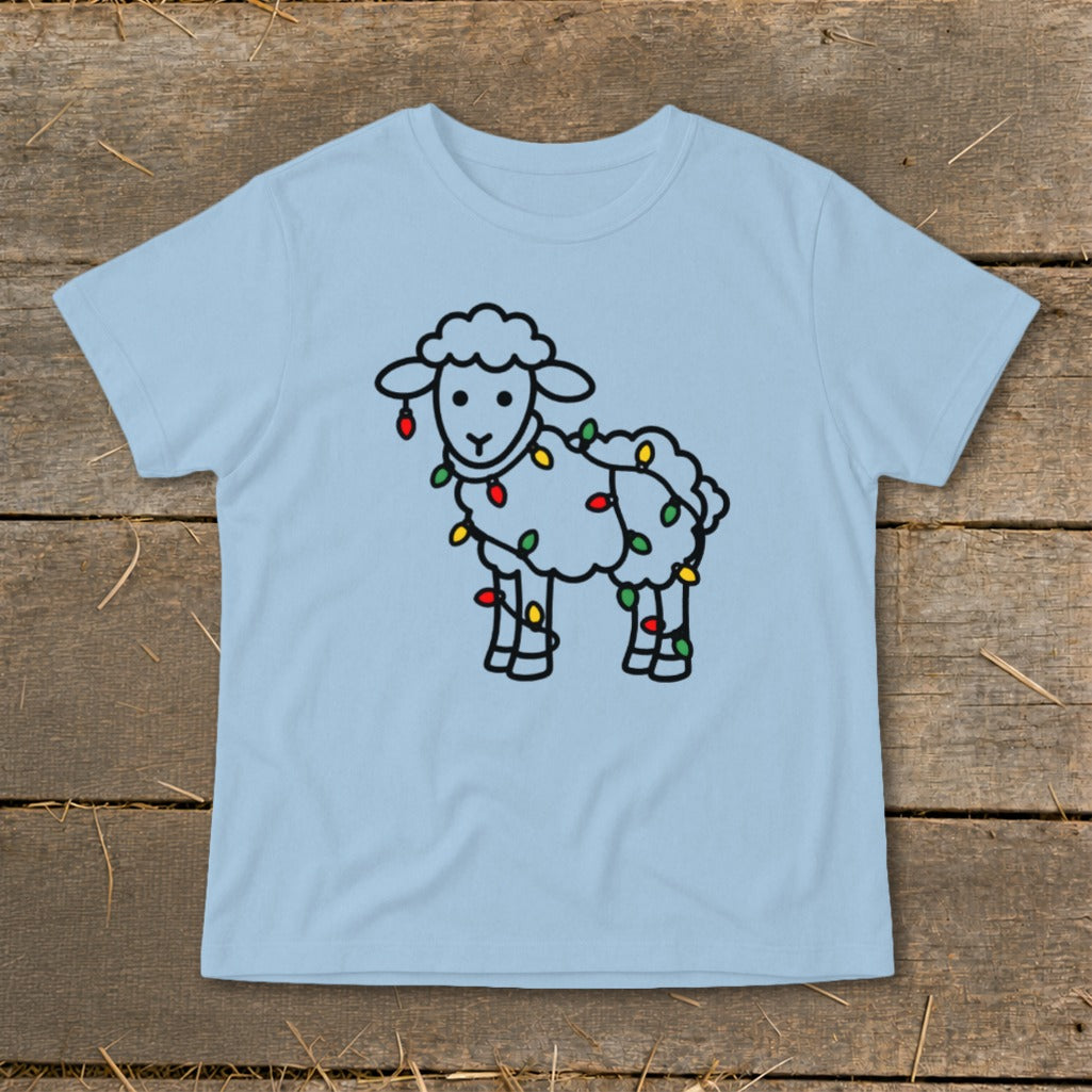 Light blue t-shirt featuring a cartoon sheep tangled in colorful holiday lights on a wooden background.