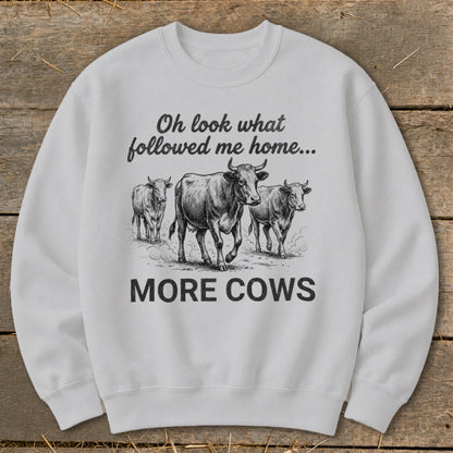 White sweatshirt with sketch of three cows and text "Oh look what followed me home... MORE COWS".