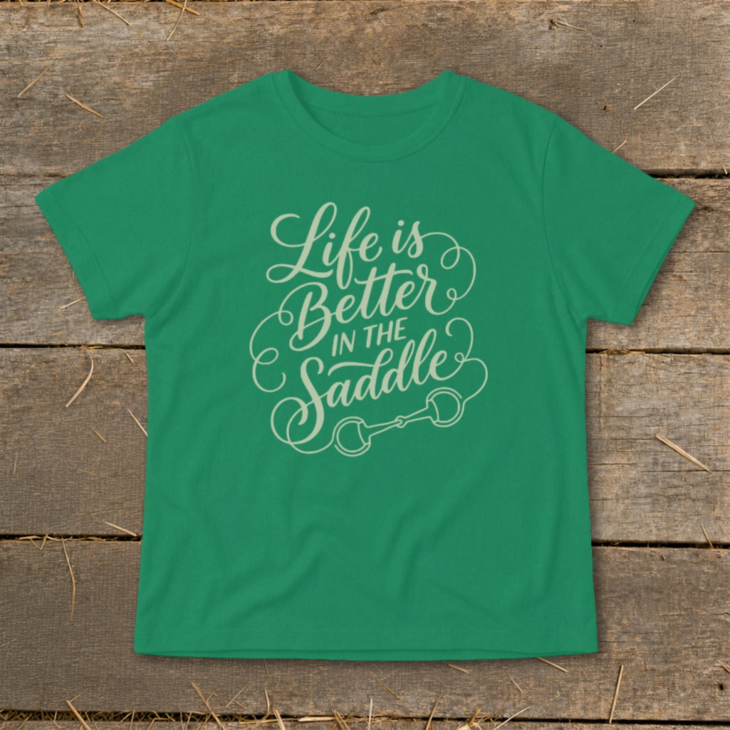 Green t-shirt with "Life is Better IN THE Saddle" text and horse bit graphic.