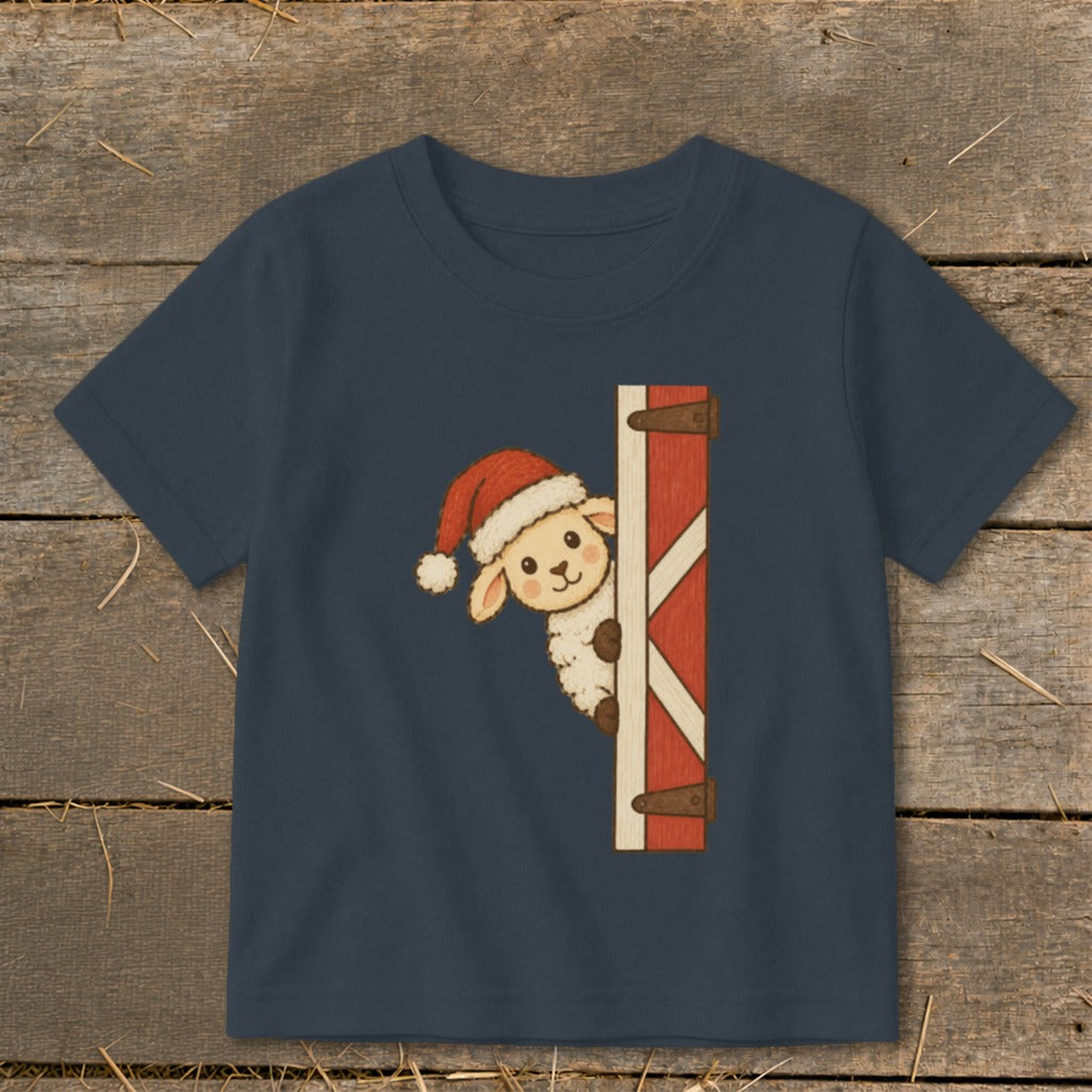 T-shirt with a sheep in a Santa hat peeking from behind a barn door.