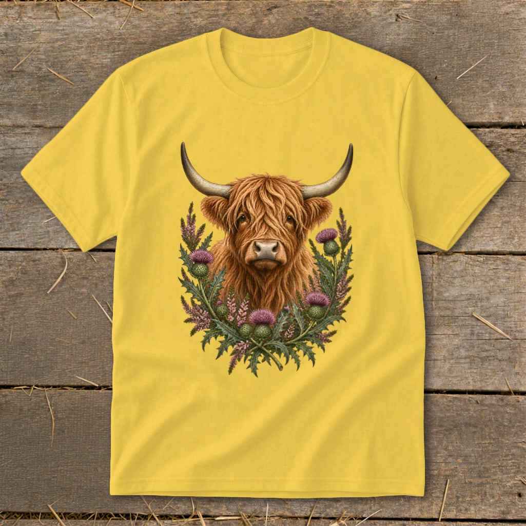 Yellow t-shirt featuring a Highland cow illustration surrounded by thistles and heather.