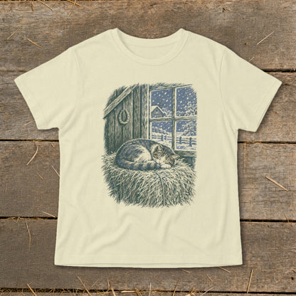 T-shirt graphic of a cat sleeping on hay by a window with snow falling.