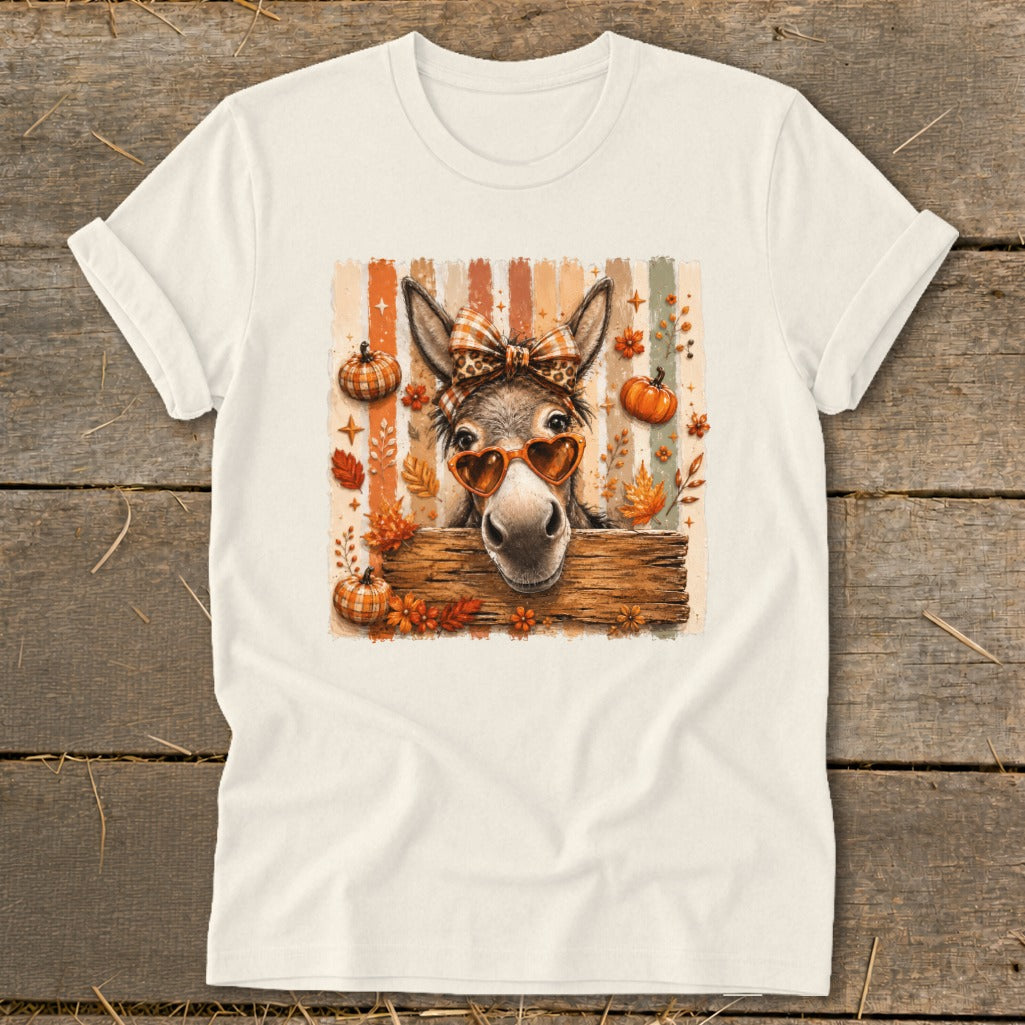 Donkey wearing heart sunglasses and plaid bow on striped background with pumpkins and leaves.