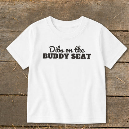 White t-shirt with black text "Dibs on the BUDDY SEAT"