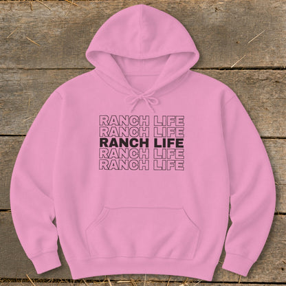A pink hooded sweatshirt featuring stacked black text reading Ranch Life on a wooden background.