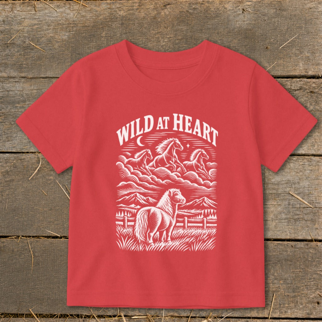 A red t-shirt with a white graphic print of horses, mountains, and the text Wild at Heart.