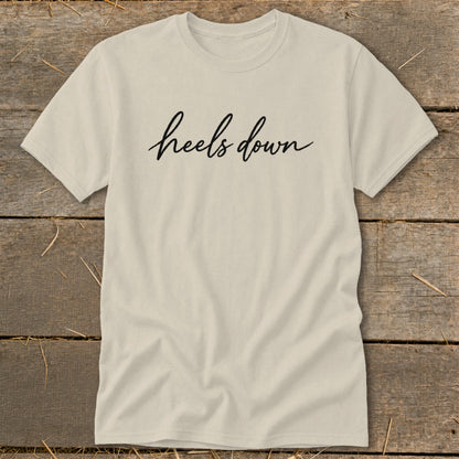 Cream t-shirt with black cursive text that reads "heels down".