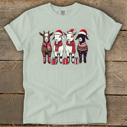 Four goats in Santa hats and festive scarves stand with presents.