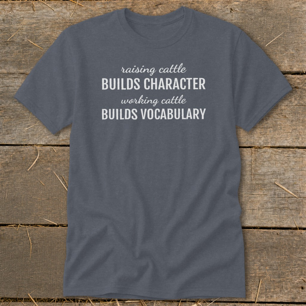 Gray t-shirt with white text reading "raising cattle BUILDS CHARACTER working cattle BUILDS VOCABULARY".