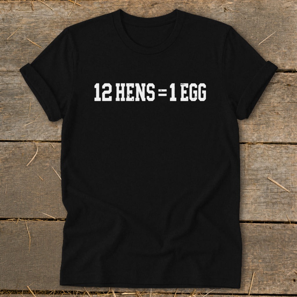 Black short-sleeve t-shirt with rolled cuffs featuring the white text 12 HENS = 1 EGG laid flat on wood.