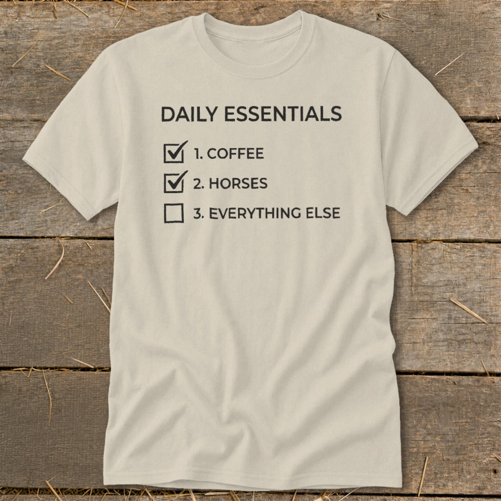 Light beige t-shirt with "Daily Essentials" checklist: 1. Coffee, 2. Horses, 3. Everything Else.