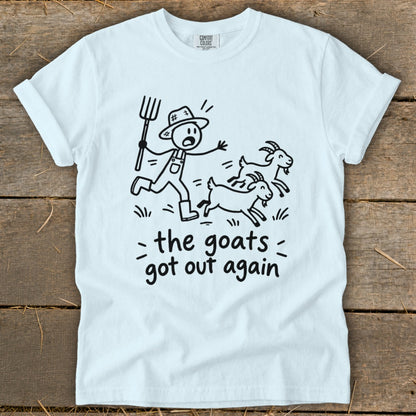 White t-shirt with a cartoon of a farmer chasing goats, text reads "the goats got out again".