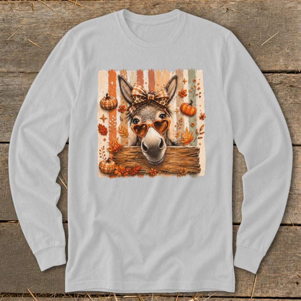 Donkey with heart sunglasses and bow over wooden sign with autumn leaves and pumpkins.