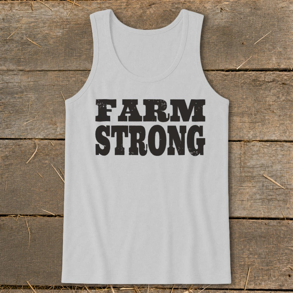 Light gray men's tank top with the distressed black text "FARM STRONG" on a rustic wooden background.