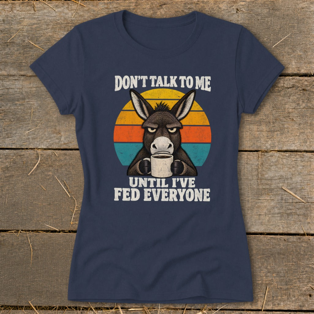 A dark blue t-shirt printed with a grumpy donkey drinking coffee and text reading Don't Talk to Me Until I've Fed Everyone.
