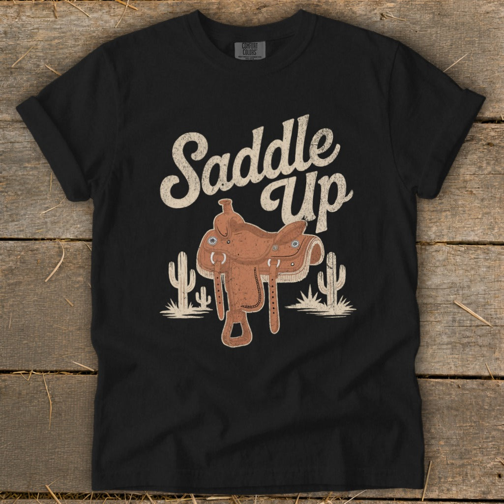 Black t-shirt with "Saddle Up" text and cowboy saddle graphic with cacti.