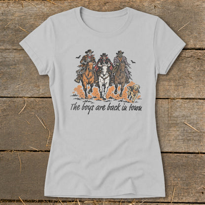 Skeleton, vampire, and zombie cowboys ride horses with a dog, text reads "The boys are back in town."