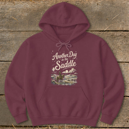 Maroon hoodie with "Another Day in the Saddle" text and horse rider graphic.