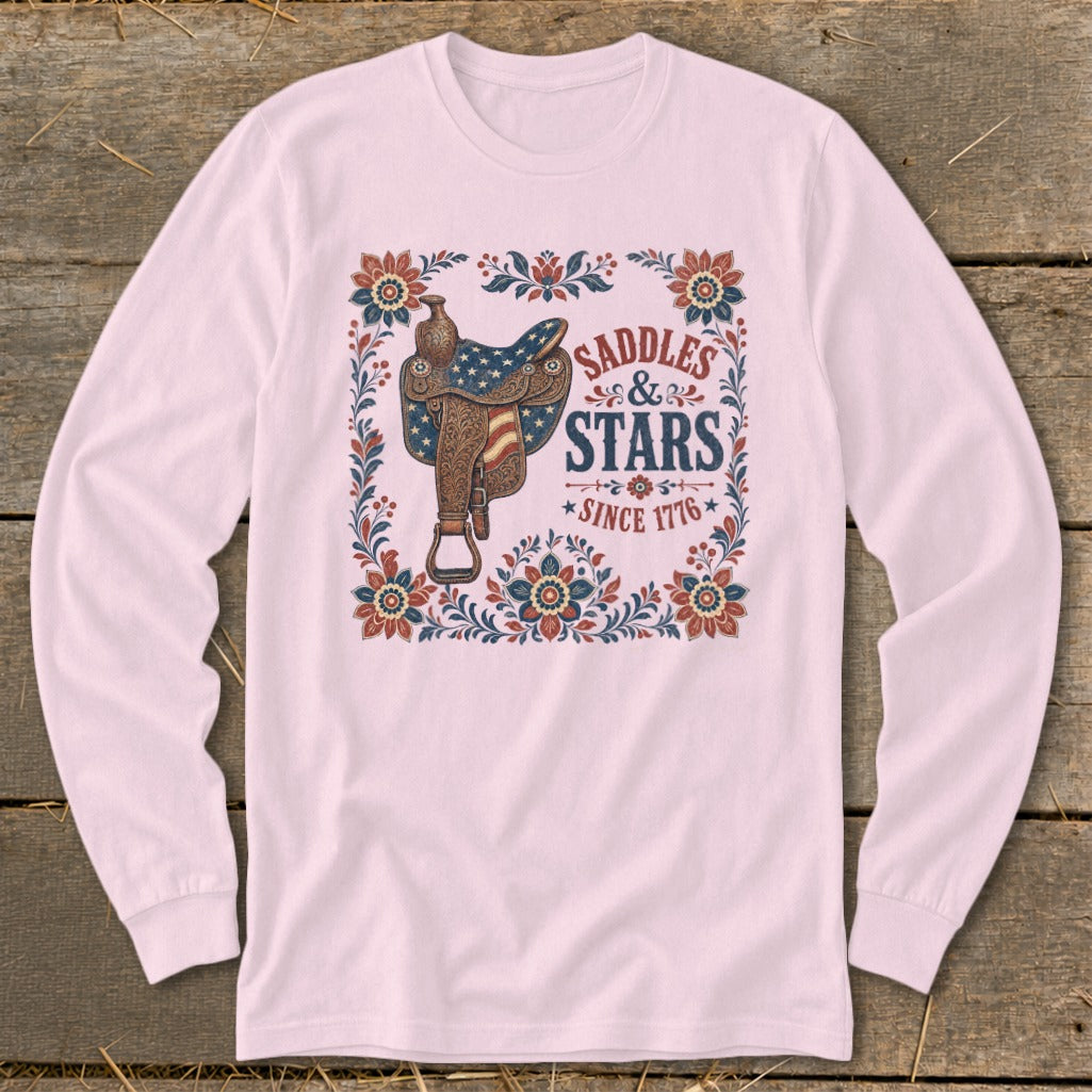 Pink long-sleeve shirt with "Saddles & Stars Since 1776" text and patriotic saddle graphic.