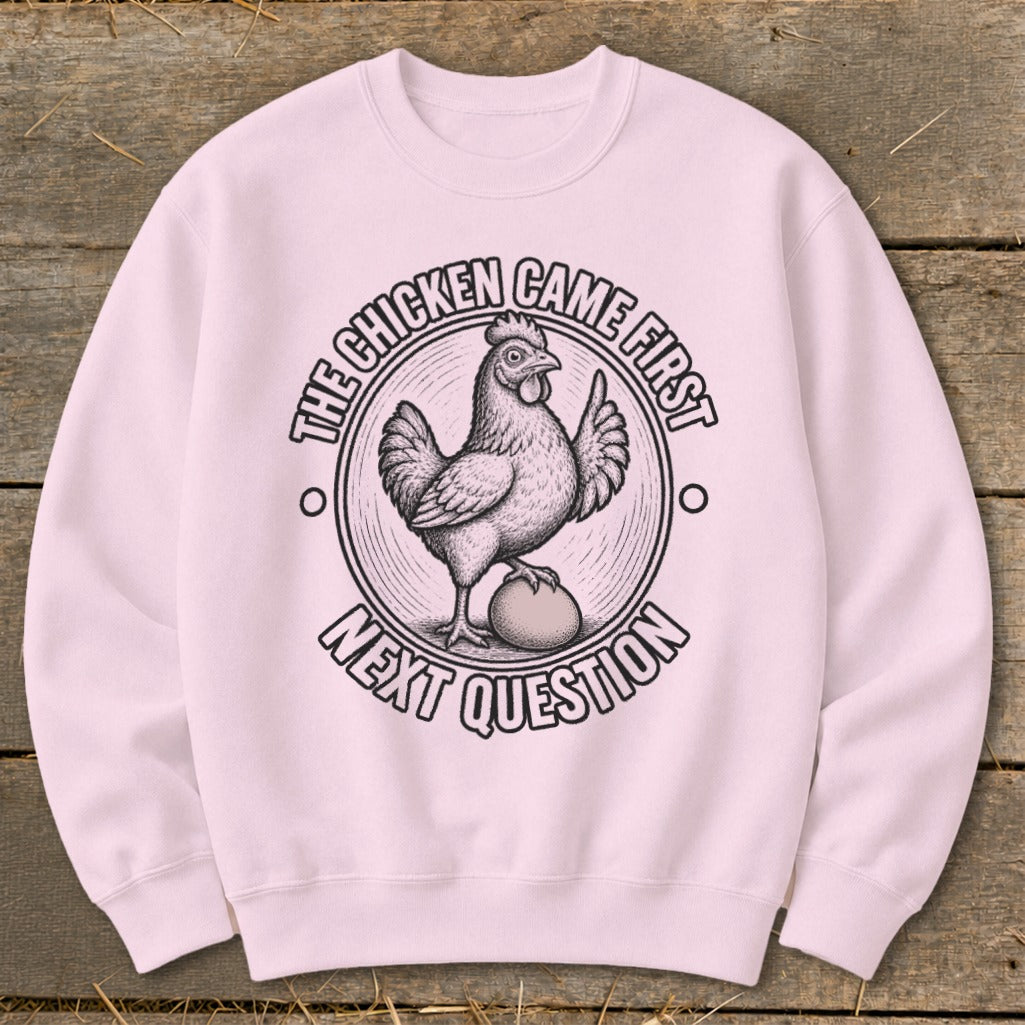 Light pink sweatshirt with graphic of chicken standing on egg, text "The chicken came first next question".