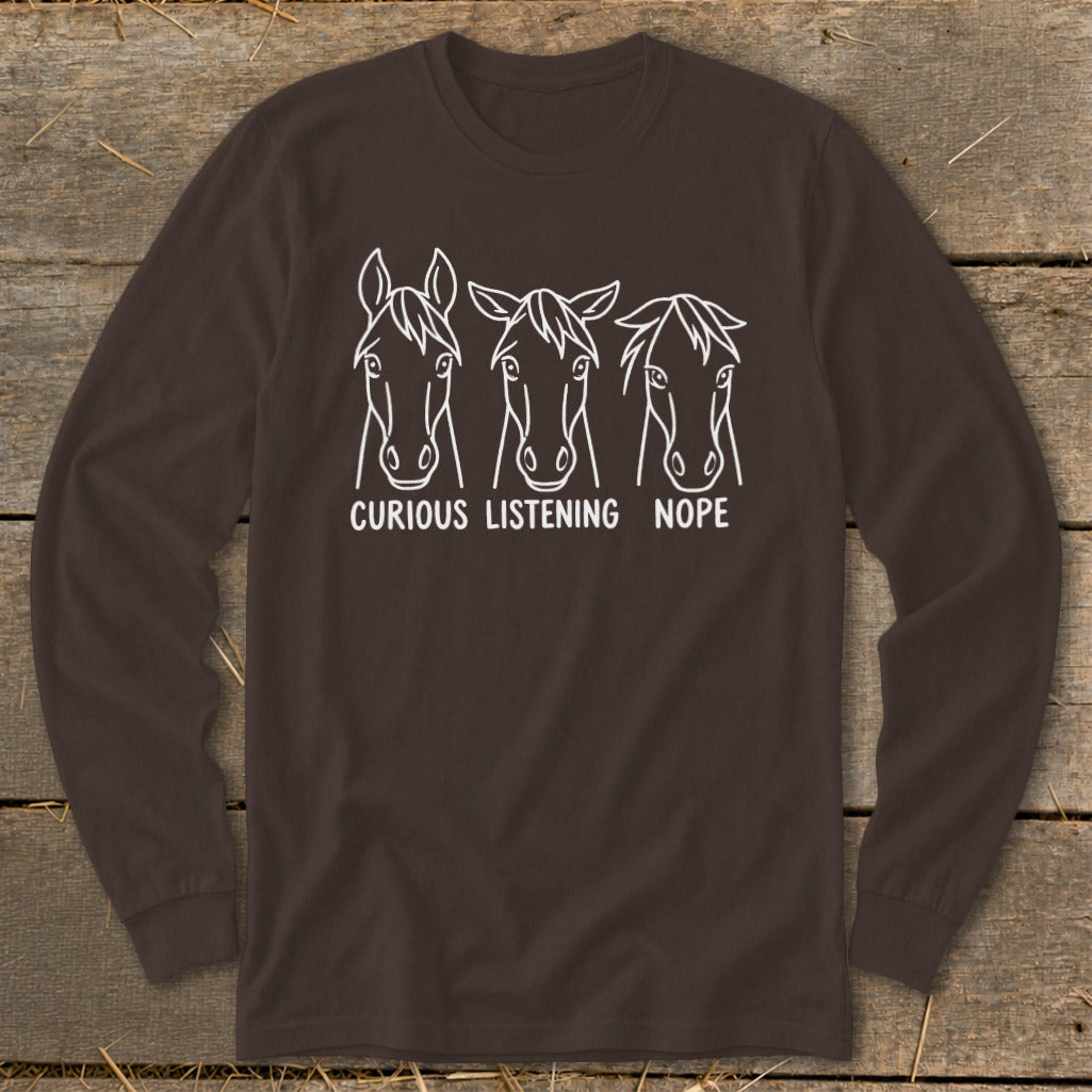 Brown long-sleeve t-shirt featuring a white graphic of three horse heads with the captions "CURIOUS," "LISTENING," and "NOPE."