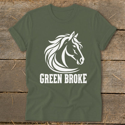 Olive green t-shirt with a white horse head graphic and the text GREEN BROKE on a wooden background.