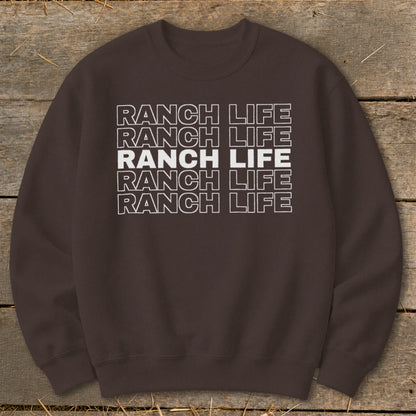 Brown crewneck sweatshirt printed with the repeating white text Ranch Life laid flat on wooden boards.
