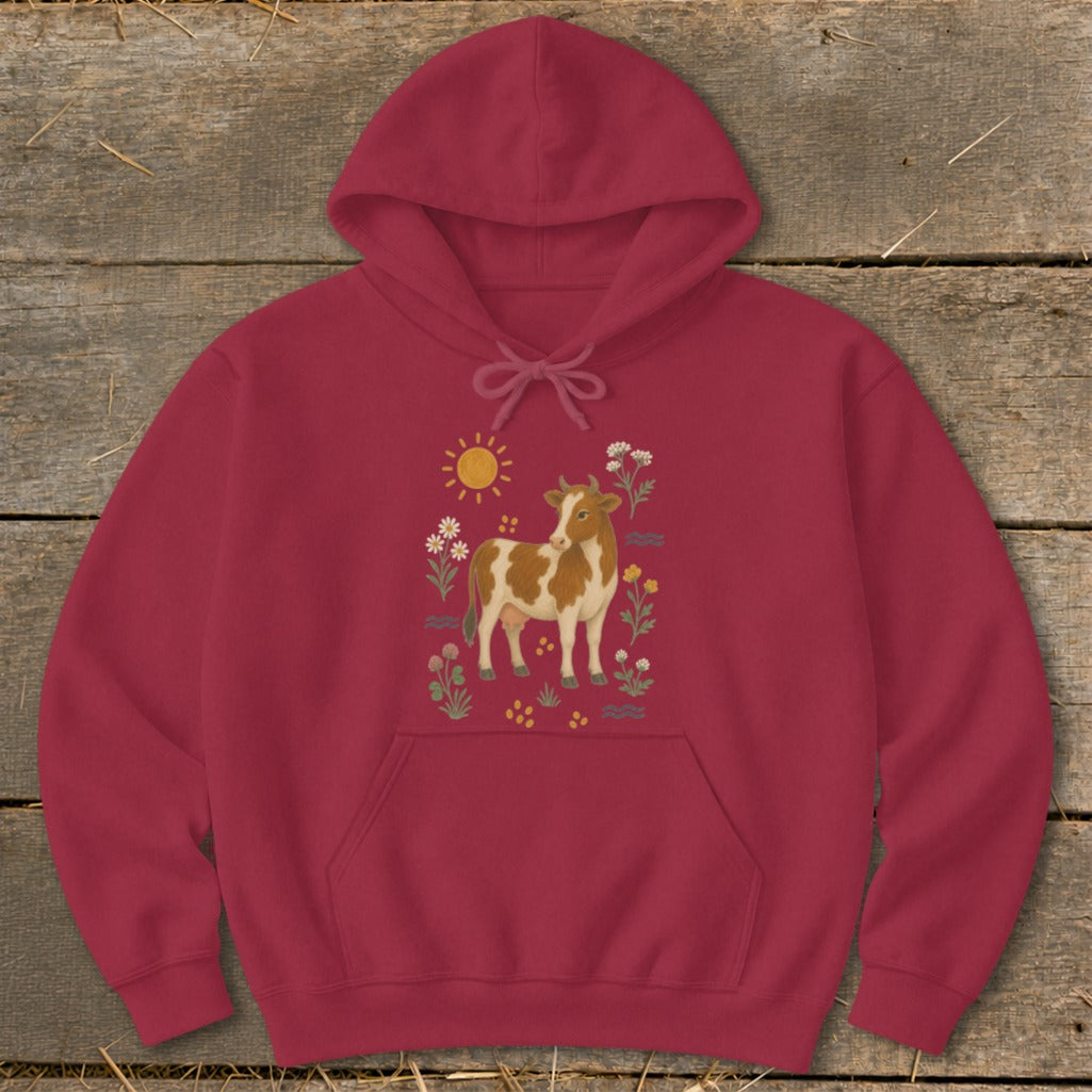 Maroon hoodie with a brown and white cow surrounded by flowers and a sun.