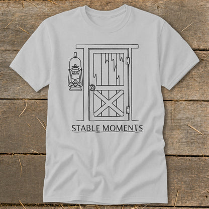 Light gray t-shirt with a line drawing of a barn door and lantern, text reads "STABLE MOMENTS".