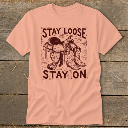 Peach t-shirt with "STAY LOOSE STAY ON" text and western saddle and boots graphic.