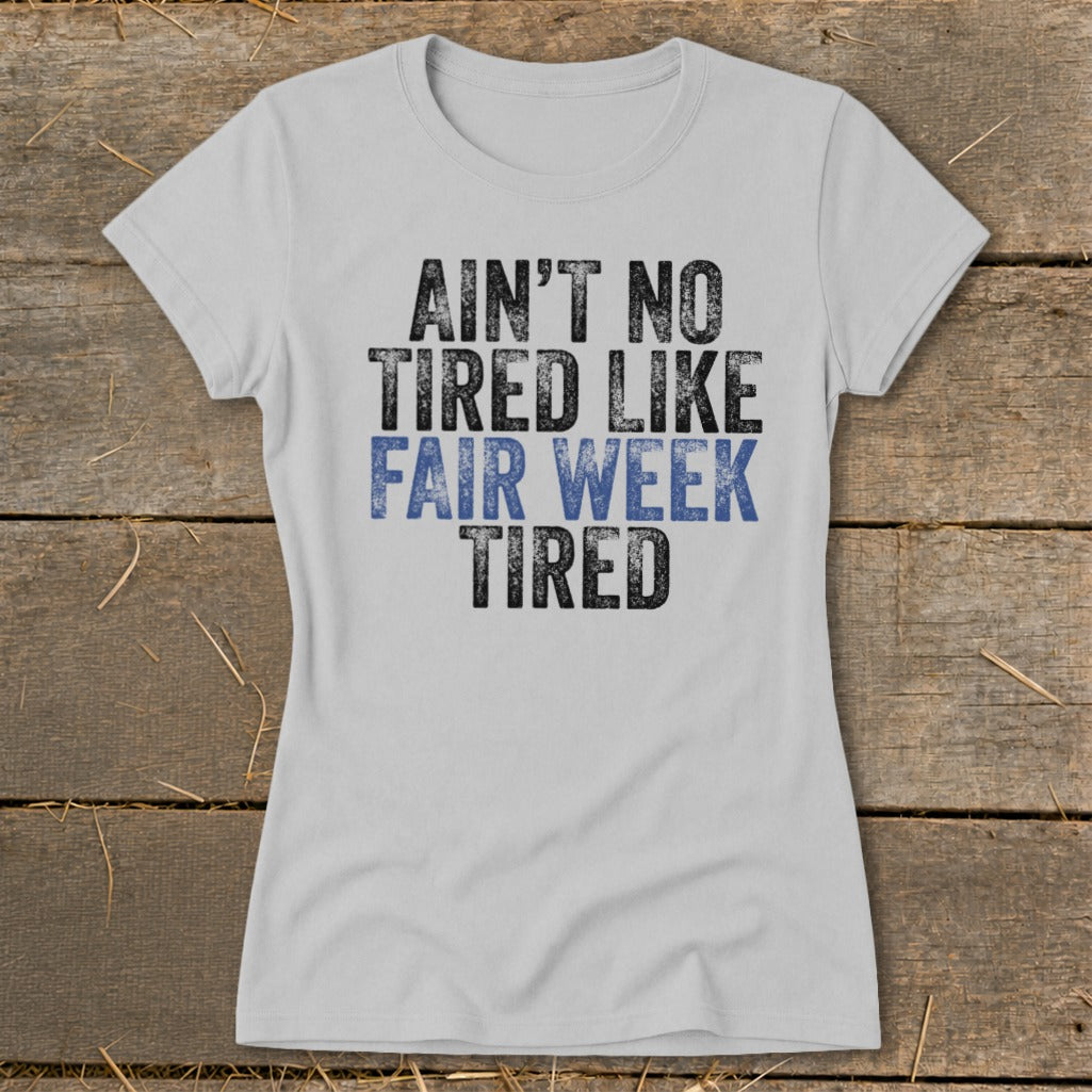 Light grey t-shirt with black and blue text reading "Ain't No Tired Like Fair Week Tired".
